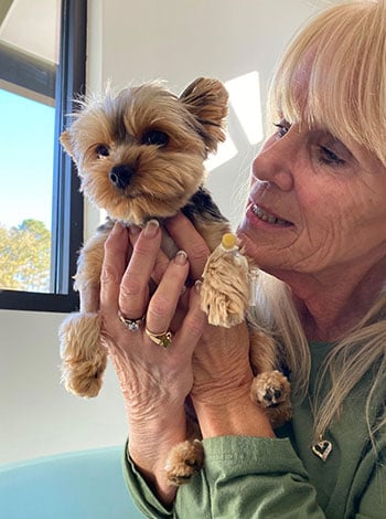 woman holding a small yorkie dog in front of a window